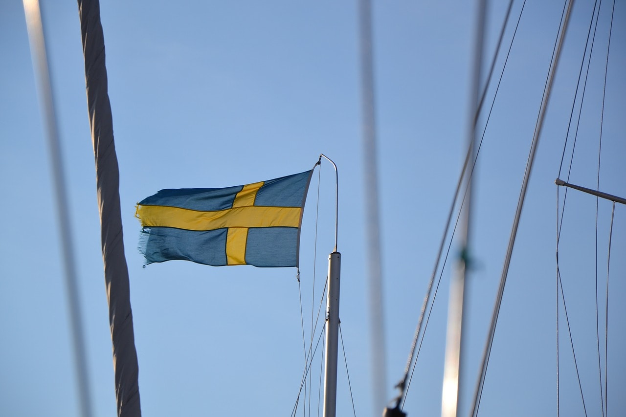 Un vol Suède pas cher avec Algofly illustré par le drapeau national jaune et bleu flottant sur le mât d'un bateau.