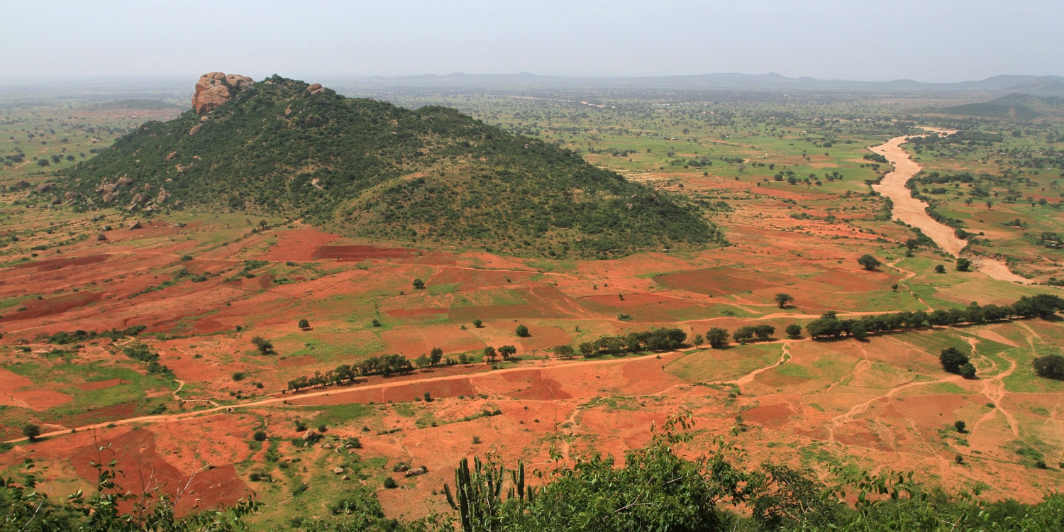 Un vol Tanzani pas cher avec Algofly illustré par un paysage de champs et de terre de couleur orange.